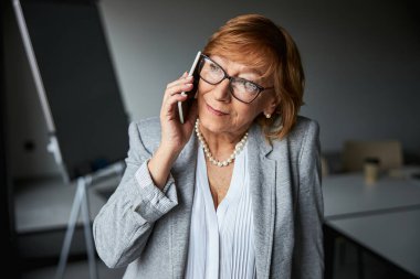 Hoş bir telefon konuşması yapan olgun, neşeli bir kadın.