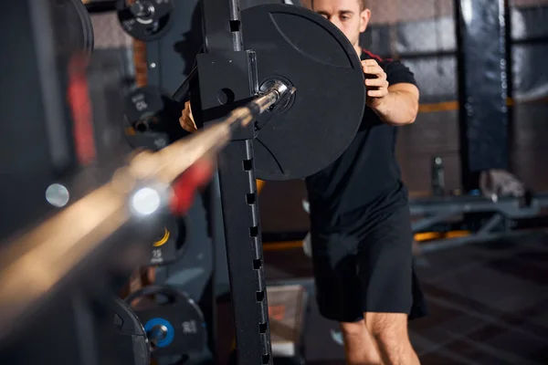 Treinador de fitness que trabalha duro fixando pesos em uma barra — Fotografia de Stock