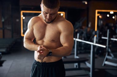 Sakin yakışıklı vücut geliştirici saatine bakıyor.