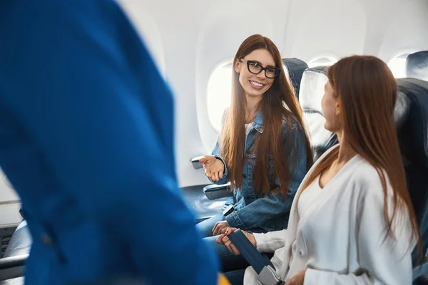Dvě dámy komunikují v letadle a usmívají se — Stock fotografie