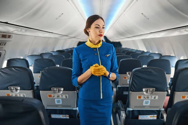 Linda aeromoça caucasiana em pé calmamente no avião — Fotografia de Stock
