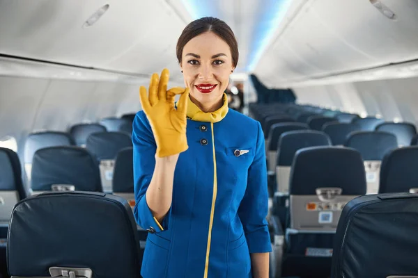 Hospedeira aérea feminina confiante mostrando gesto OK no trabalho — Fotografia de Stock