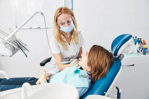 Orthodontist drilling boy side teeth with handpiece — Stock Photo, Image