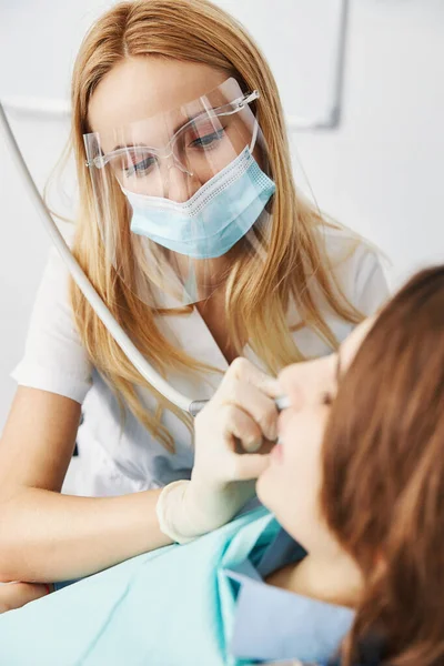 Zorgvuldige tandheelkundige expert verwijderen cariës van jongen tanden met handstuk — Stockfoto