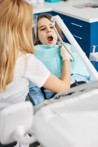 Стоматолог, использующий воздушный наконечник для распыления воды на мальчика — стоковое фото