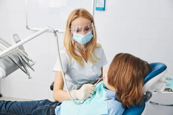 Female medical worker spraying boy teeth from air water syringe — Stock Photo, Image