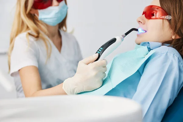 Dental curing light fixing composite resin fillers in boy teeth — Stock Photo, Image