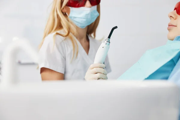 Doctor in masker brengen tandheelkundige genezen licht aan kind mond — Stockfoto