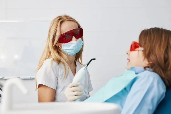 Dentysta przygotowujący protezę zębów chłopca światłem utwardzającym — Zdjęcie stockowe