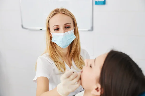 Donna in maschera installazione di riempimento dentale nei denti del paziente — Foto Stock