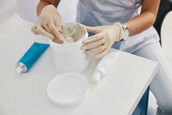 Dentist taking dental impression compound from bucket with spoon — Stock Photo, Image