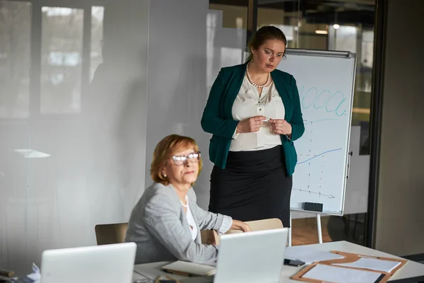 Anställda står tyst nära whiteboard med chefen tittar mot fönstret — Stockfoto