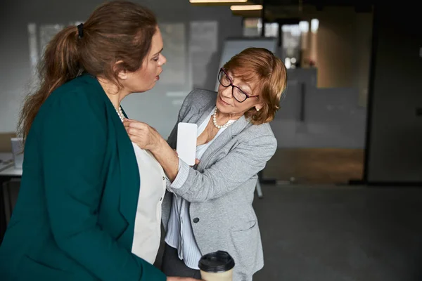 Geschäftsfrau checkt ihre Mitarbeiter-Halskette aus — Stockfoto