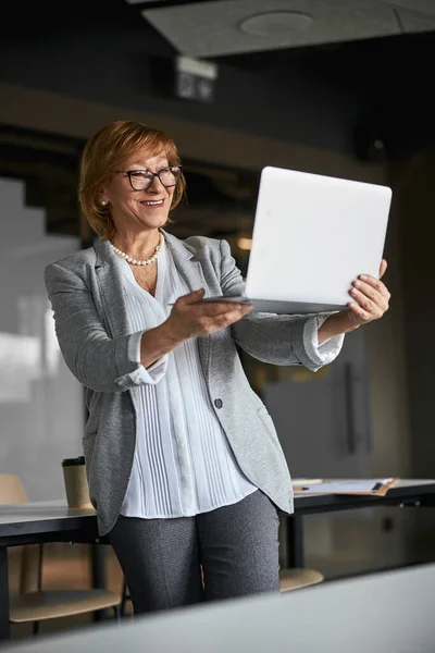 Lächelnde Mitarbeiterin starrt auf den Bildschirm ihres Laptops — Stockfoto