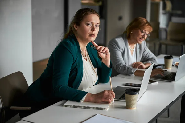 Dicke Frau blickt während der Arbeit am Laptop in die Kamera — Stockfoto