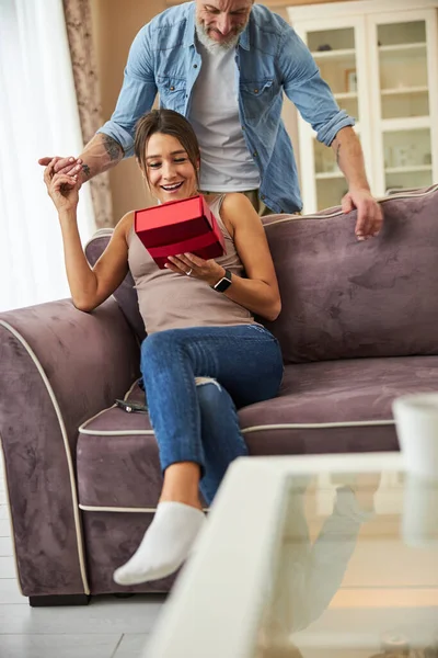 Şaşırmış kadın kırmızı hediye kutusuna bakıyor.