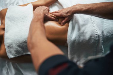 Sağlık merkezindeki havlunun altında masaj masasında uzanan zarif genç bayan.