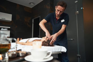 Masaj masasındaki zarif kadın sağlık kliniğinde yeni masaj teknikleri öğreniyor.