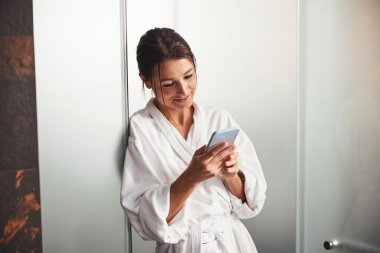 Göz kamaştırıcı esmer, beyaz kadın. Kapalı bir odada cep telefonuna mesaj yazıyor.