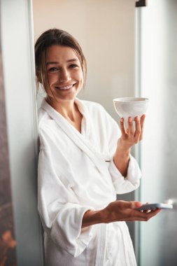Cep telefonlu zarif bir iş kadını güzellik merkezindeki fotoğraf makinesine bakıyor.