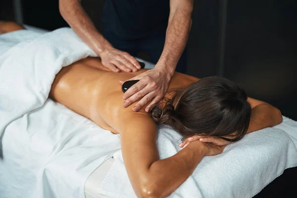 Чарівна молода приємна леді під рушником насолоджується новою технікою масажу в спа-салоні — стокове фото