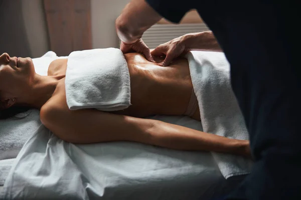 Charmig ung kvinna avkopplande magen massage på spa salong — Stockfoto