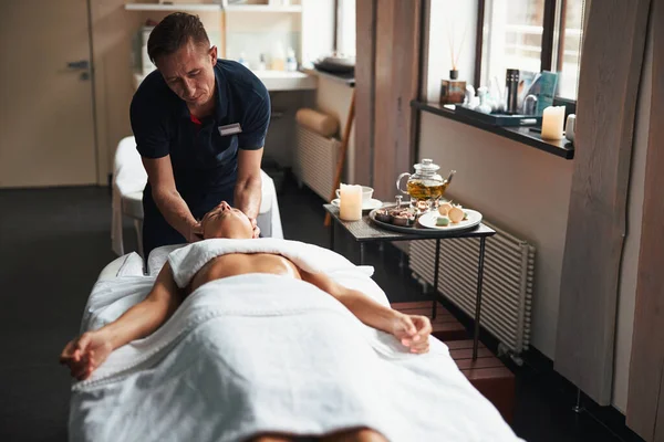 Mooie jonge dame liggend op massagetafel en ontspannen bij de manuele therapie in gezondheidscentrum — Stockfoto