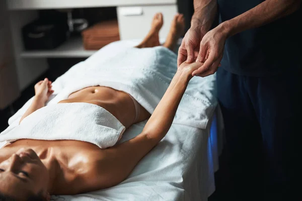 Mooie charmante vrouw onder de handdoek liggend op massagetafel het ontvangen van nieuwe massage techniek in wellness centrum — Stockfoto
