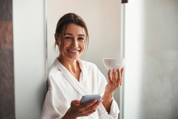 Feliz sorrindo mulher bonita segurando copo branco na mão no quarto dentro de casa — Fotografia de Stock