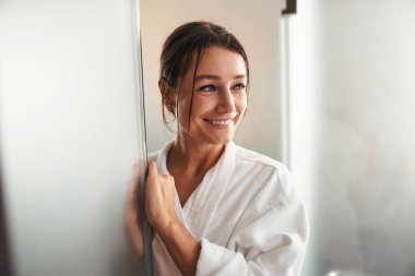 Beyaz bornozlu esmer, çekici beyaz kadın spa salonunda dinleniyor.