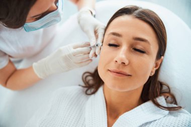 Kadın hasta kırışıklıklar için deri altı enjeksiyonu yaptırıyor.