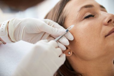 Koyu saçlı, beyaz bir kadın mezoterapi görüyor.