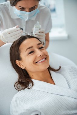 Kozmetikçi hastanın cildine cilt bakımı yapıyor.