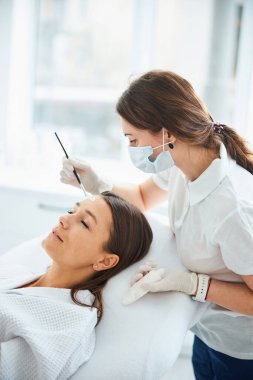 Kozmetik uzmanı kozmetik fırçasıyla maske takıyor.
