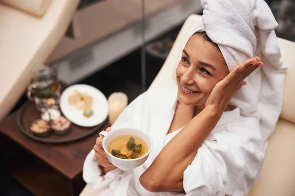 하얀 목욕 가운을 입고 스파 리조트 호텔에서 미소짓고 있는 갈색 머리 여자가 쉬고 있다 — 스톡 사진