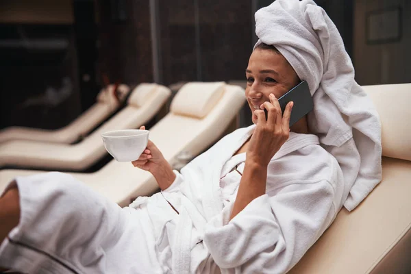 Hermosa mujer de negocios bonita elegante beber bebidas mientras está sentado en la silla de cubierta en el hotel balneario —  Fotos de Stock