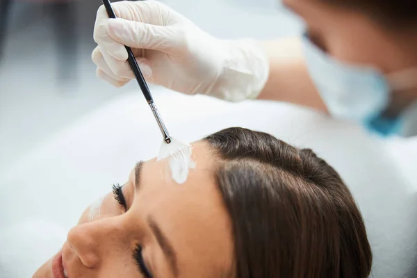 Dermatolog applicera ett näringsämne mask på den kvinnliga pannan — Stockfoto