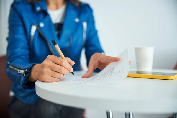 Spa client in a trendy leather jacket signing a consent form — Stock Photo, Image