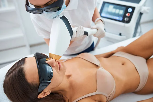 Médico quitando el pelo no deseado de su labio superior paciente — Foto de Stock