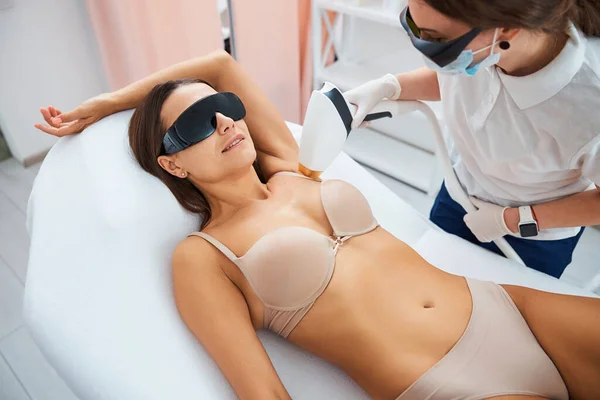 Mujer con gafas de seguridad sonriendo durante un procedimiento médico no invasivo — Foto de Stock