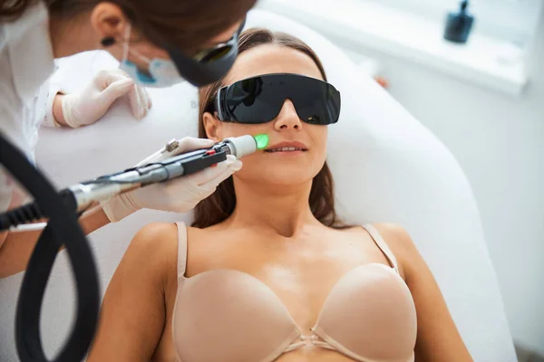 Esteticista haciendo una depilación láser en la cara del paciente — Foto de Stock