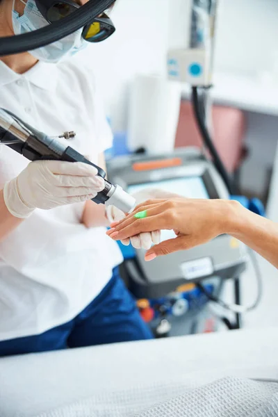 Esteticista que conduz um procedimento de remoção de cabelo em uma mão feminina — Fotografia de Stock