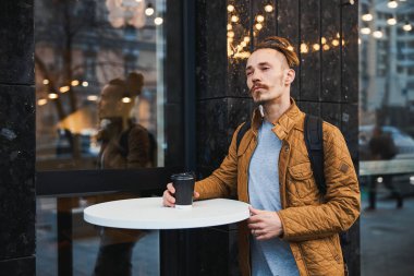 Düşünceli yakışıklı adam kahvesiyle poz veriyor.