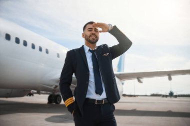 Mutlu pilot elleriyle gözlerini güneşten koruyor.