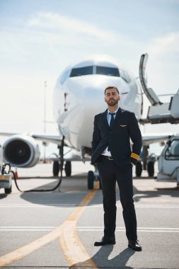 Deneyimli pilot yolcu uçağının yanında poz veriyor.