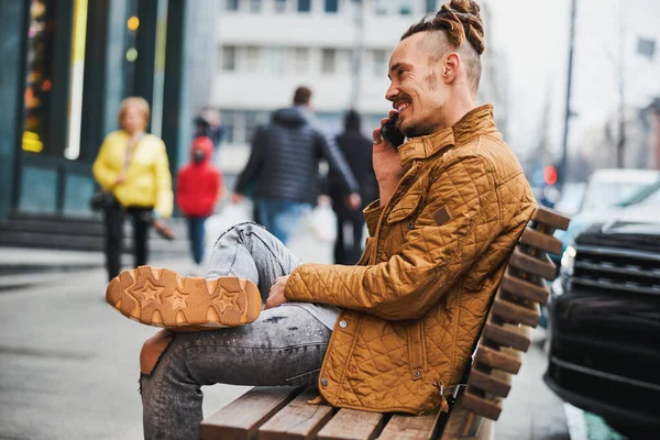 Šťastný mladý muž těší rozhovor na telefonu venku — Stock fotografie