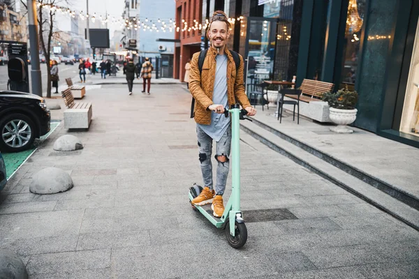 Joven alegre montando su scooter en la calle — Foto de Stock