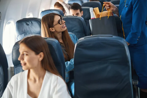 Tacksamma passagerare som lämnar över sitt paket till flygvärdinnan — Stockfoto