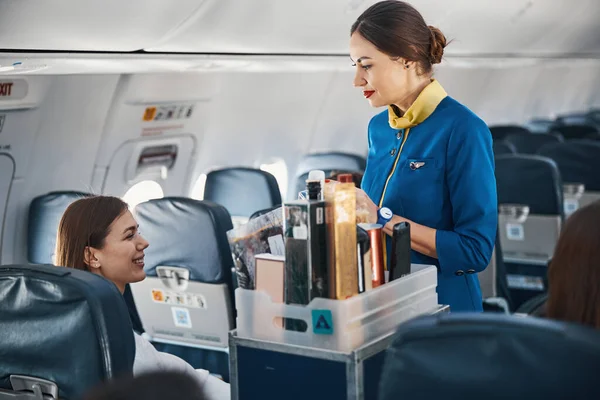 Женщина в самолете обращается к стюардессе с тележкой с едой — стоковое фото