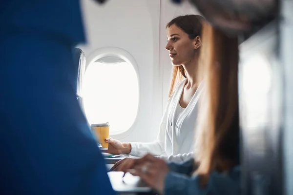Vrouwelijk zittend met koffie op haar vliegtuigstoel — Stockfoto